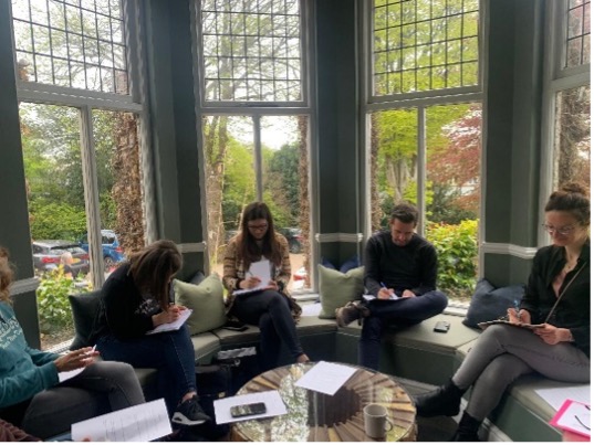 Students writing together during a tailored English retreat in a sunlit bay-window lounge